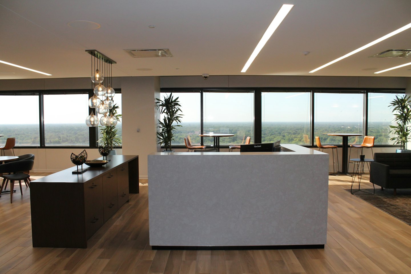 Moderne Bürorezeption mit grauem Schreibtisch und Holzsideboard.
