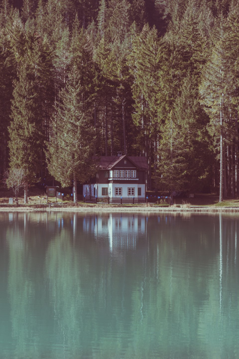 Zweistöckiges Haus mit rotem Dach neben einem See.