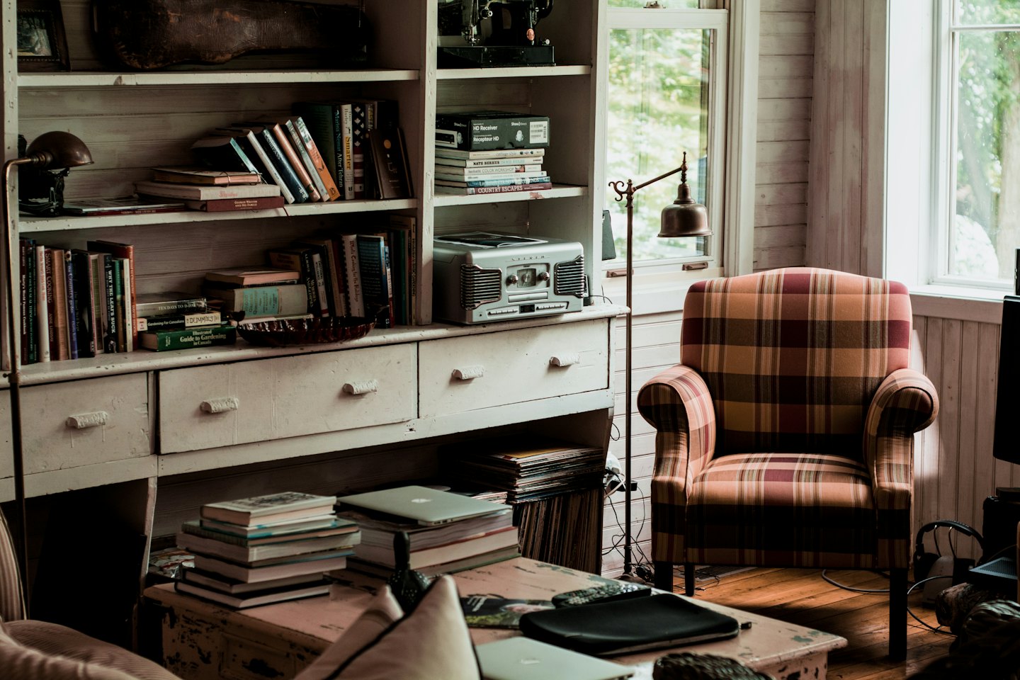 Rustikales Wohnzimmer mit Bücherregal und kariertem Sessel am Fenster.